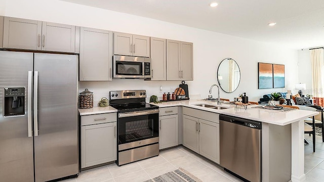 kitchen featuring light tile patterned floors, kitchen peninsula, appliances with stainless steel finishes, gray cabinetry, and sink