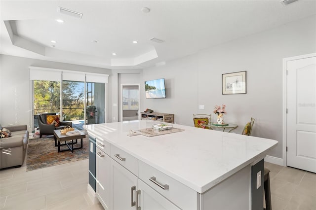 kitchen featuring a raised ceiling, white cabinetry, a center island, and light tile patterned floors