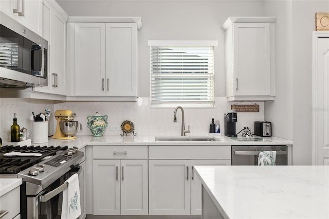 kitchen featuring white cabinetry, sink, backsplash, and appliances with stainless steel finishes