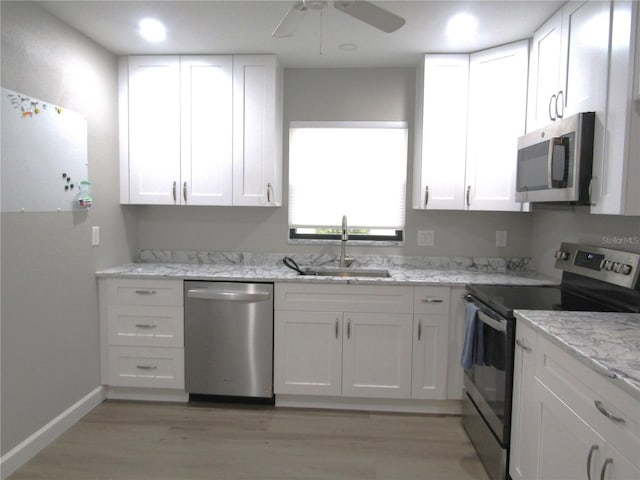 kitchen with stainless steel appliances, white cabinetry, sink, and light wood-type flooring