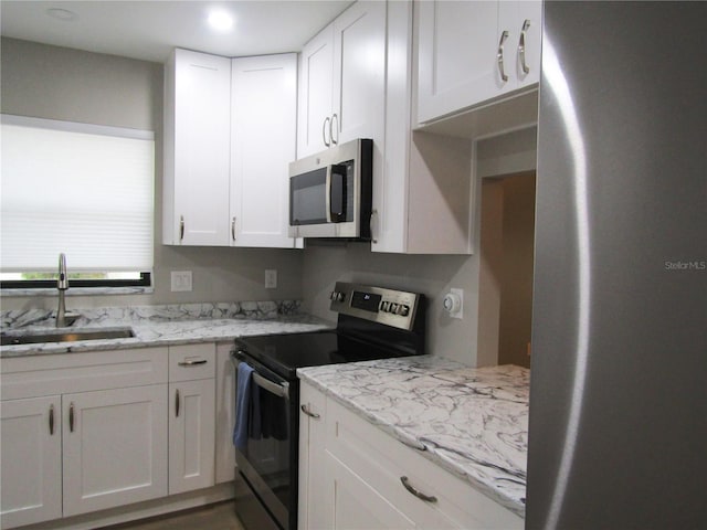 kitchen featuring white cabinetry, appliances with stainless steel finishes, sink, and light stone counters