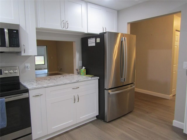 kitchen with stainless steel appliances, light hardwood / wood-style floors, and white cabinets