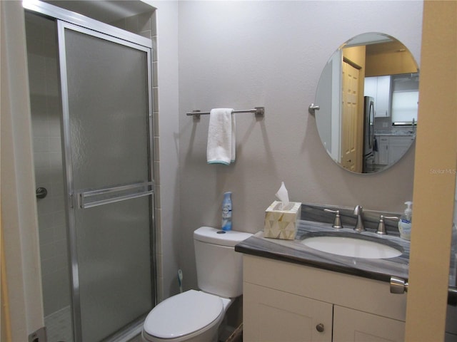 bathroom featuring vanity, toilet, and a shower with shower door