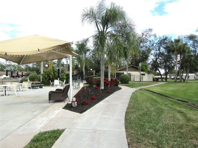 view of property's community featuring a lawn and a patio