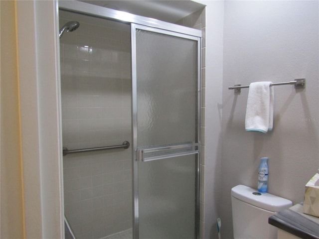 bathroom featuring toilet and a shower with door