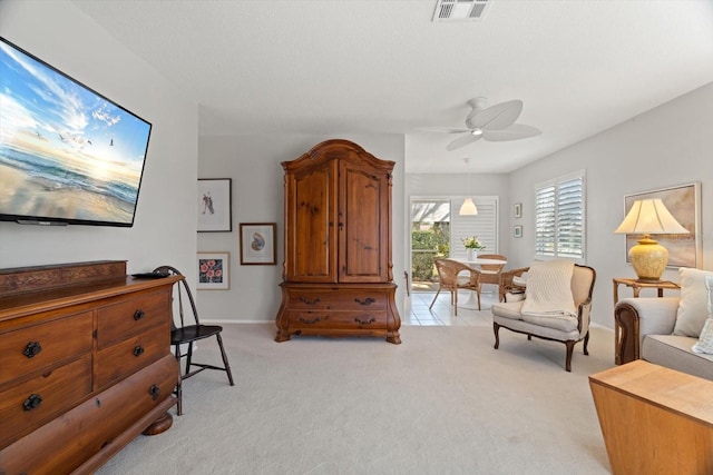 living area featuring light carpet and ceiling fan