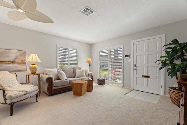 carpeted living room featuring ceiling fan and a textured ceiling