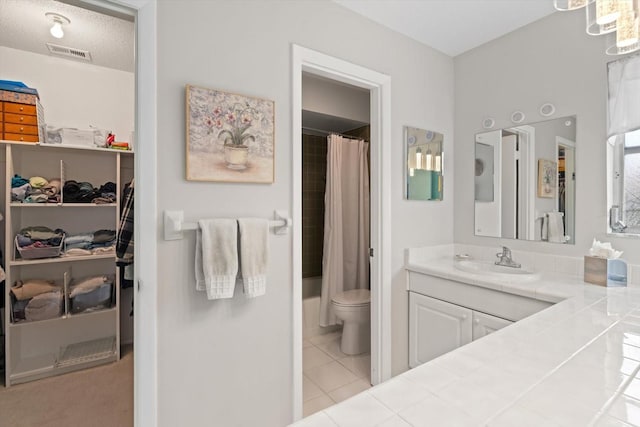 bathroom with tile patterned flooring, vanity, a textured ceiling, and toilet