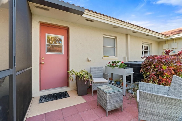 property entrance with cooling unit and a patio