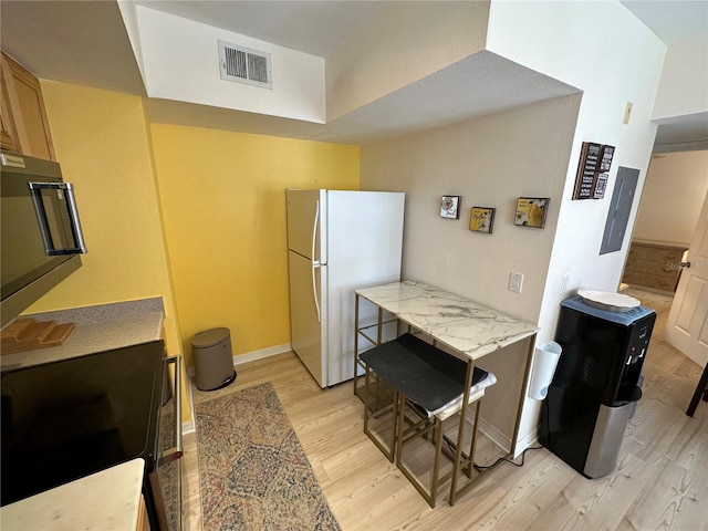 kitchen with light brown cabinets, light hardwood / wood-style floors, electric range, and white fridge