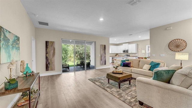 living room with light hardwood / wood-style floors and a textured ceiling