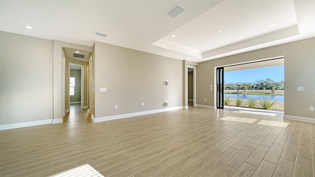 unfurnished room featuring a water view and a tray ceiling