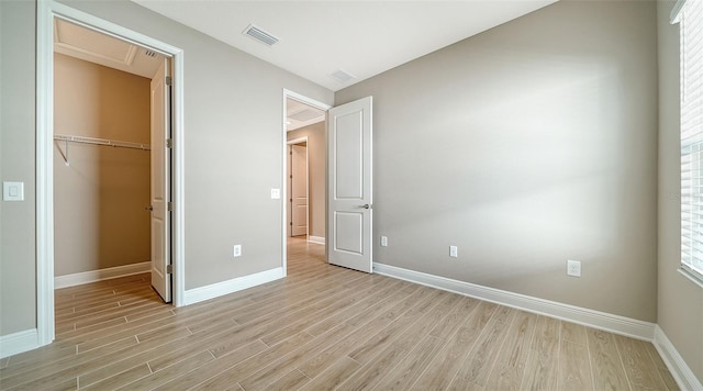 unfurnished bedroom with a walk in closet, light wood-type flooring, and a closet