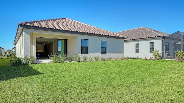 back of property with glass enclosure and a yard