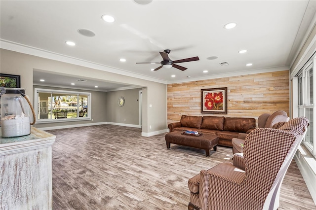 living room with light hardwood / wood-style flooring, ornamental molding, ceiling fan, and wood walls