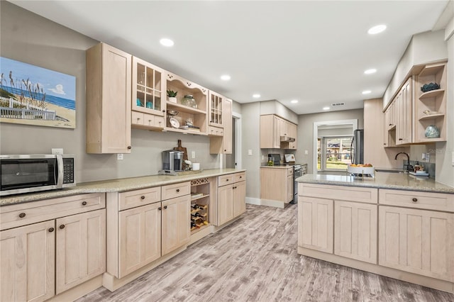 kitchen with stainless steel appliances, light hardwood / wood-style floors, and light brown cabinets