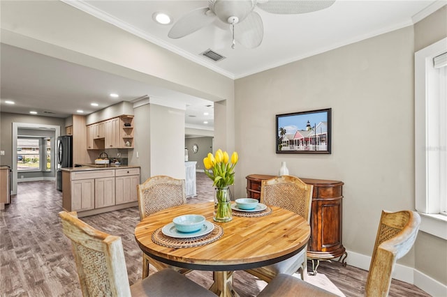 dining space with crown molding, ceiling fan, and light hardwood / wood-style floors