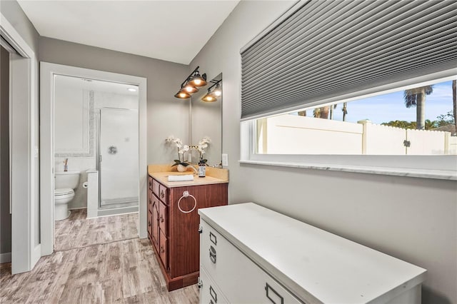 bathroom featuring vanity, wood-type flooring, a shower with door, and toilet