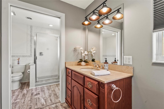 bathroom with tile walls, hardwood / wood-style flooring, vanity, toilet, and a shower with door