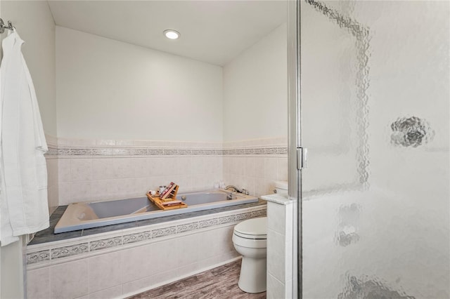 bathroom featuring wood-type flooring, toilet, and plus walk in shower