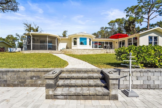 rear view of house featuring a sunroom and a yard