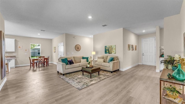 living room with a textured ceiling and light hardwood / wood-style floors