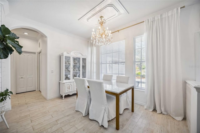 dining area with an inviting chandelier, ornamental molding, and light hardwood / wood-style flooring