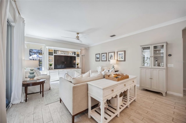 living room with ceiling fan, ornamental molding, and light wood-type flooring