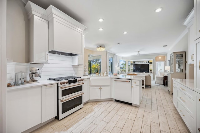 kitchen with white cabinets, decorative backsplash, light hardwood / wood-style floors, kitchen peninsula, and white appliances