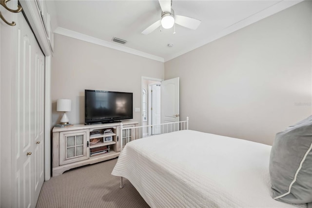 carpeted bedroom with ceiling fan, ornamental molding, and a closet