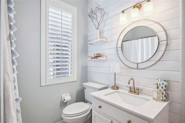 bathroom with vanity, wood walls, and toilet