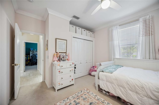 bedroom featuring crown molding, ceiling fan, light carpet, and a closet