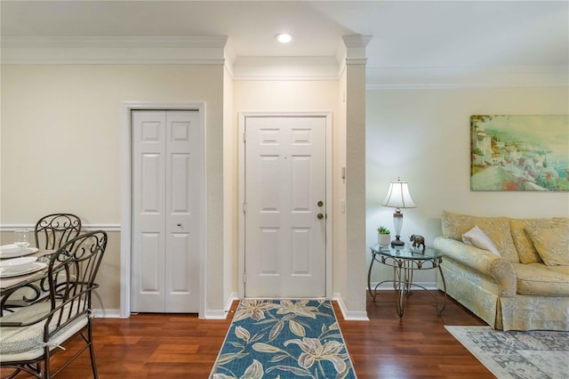 foyer entrance featuring crown molding, decorative columns, and dark hardwood / wood-style flooring