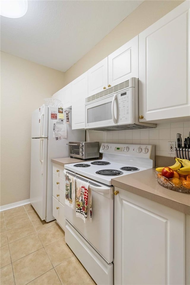 kitchen featuring light tile patterned flooring, white appliances, white cabinetry, and backsplash