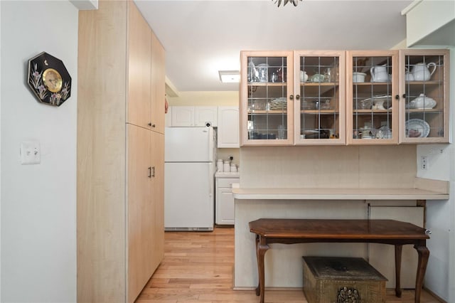 kitchen with white refrigerator, a breakfast bar area, and light hardwood / wood-style floors