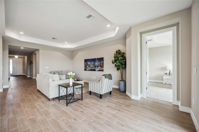 living room with a raised ceiling and light hardwood / wood-style floors