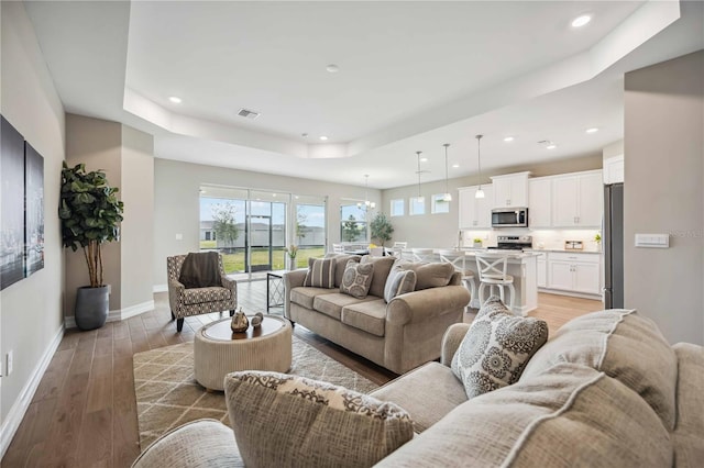 living room featuring a tray ceiling and light wood-type flooring