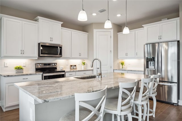 kitchen featuring sink, stainless steel appliances, and an island with sink