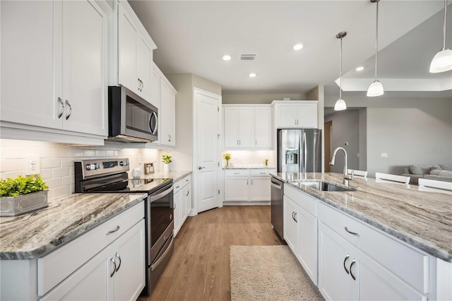 kitchen with an island with sink, stainless steel appliances, sink, and white cabinets