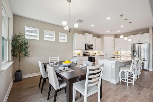 dining room featuring hardwood / wood-style flooring, sink, and a notable chandelier