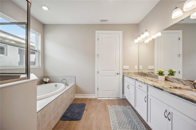 bathroom with tiled tub, vanity, and hardwood / wood-style floors