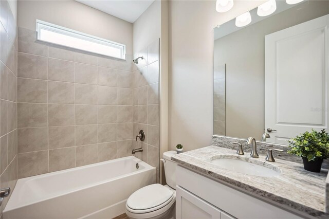 full bathroom featuring tiled shower / bath, vanity, and toilet