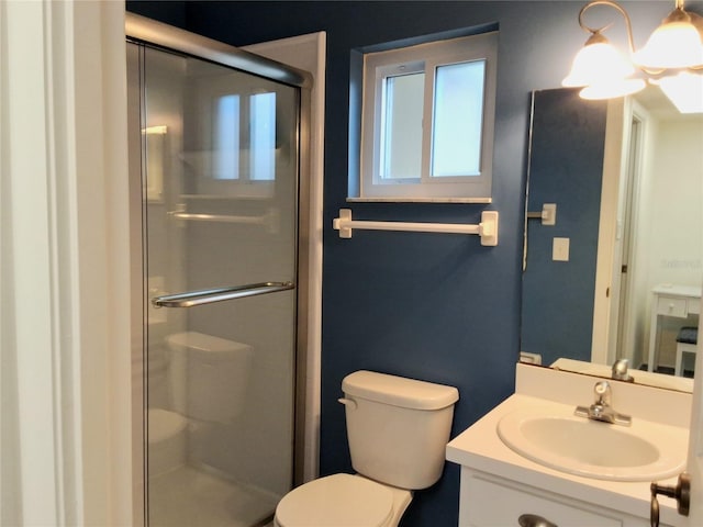 bathroom featuring a shower with door, toilet, and vanity