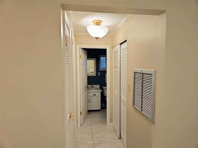 hall featuring crown molding, sink, a textured ceiling, and light tile patterned floors