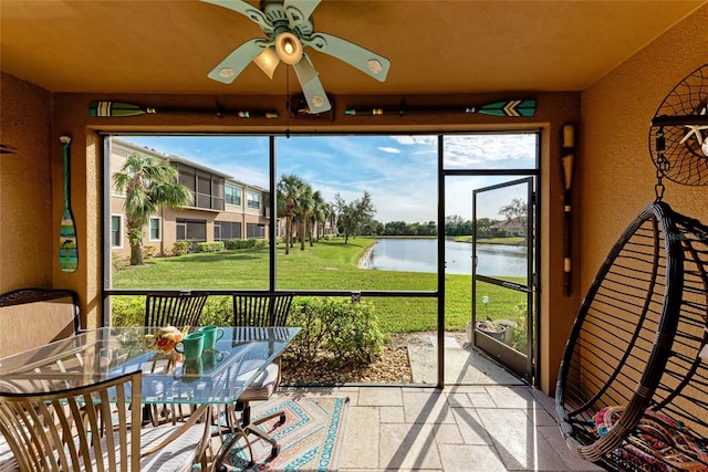 unfurnished sunroom featuring a healthy amount of sunlight, ceiling fan, and a water view