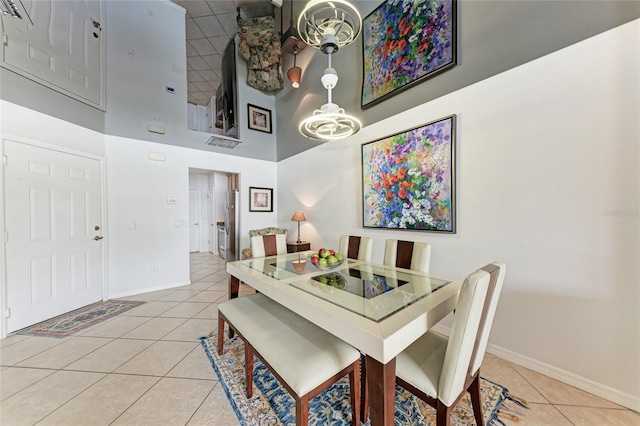 dining room featuring tile patterned flooring, a towering ceiling, and a chandelier