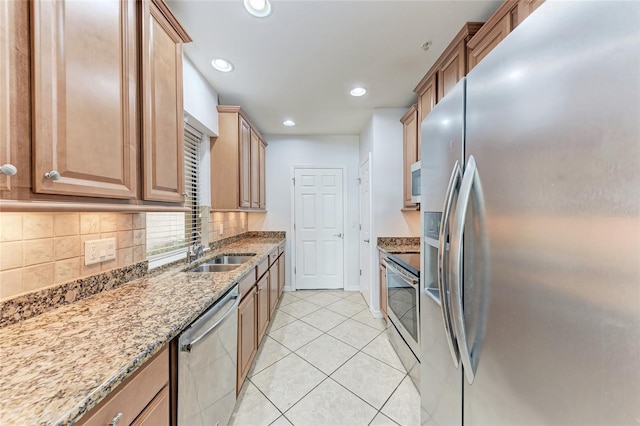 kitchen featuring sink, appliances with stainless steel finishes, light stone counters, light tile patterned flooring, and decorative backsplash