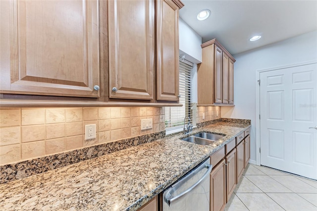 kitchen featuring sink, stainless steel dishwasher, stone counters, and light tile patterned flooring