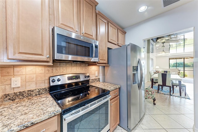 kitchen with stainless steel appliances, light tile patterned floors, backsplash, and light stone counters