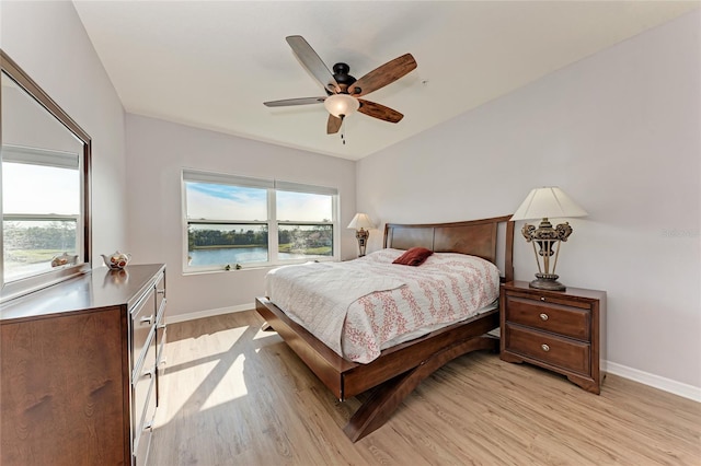 bedroom featuring a water view, ceiling fan, and light wood-type flooring